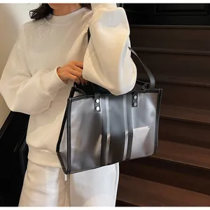 Detail view of large transparent PVC tote bag with grey stripes and black leather handle