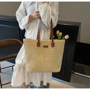 Détail d'un sac cabas en paille tissée avec anses en cuir marron et tulipes