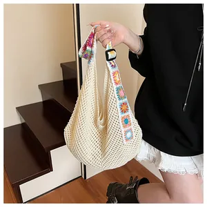 Detail of knit crochet tote bag featuring colorful floral shoulder strap and mesh texture
