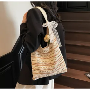Detail of striped crochet tote bag with large lace bow and bohemian knit texture