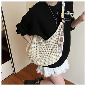 Detail of crochet tote bag with colorful floral strap and beige knitted hollow grid texture