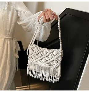 Detail of bohemian white macrame bag with woven diamond patterns and long tassels