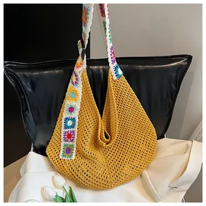 Detail of hand-crocheted yellow hobo bag featuring colorful floral shoulder strap patterns