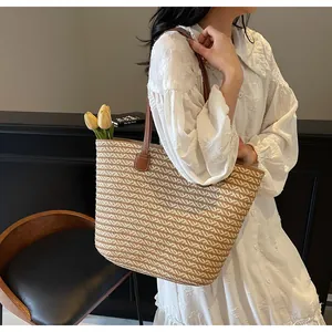 Detail of woven straw tote bag featuring brown leather shoulder straps and tulip accent
