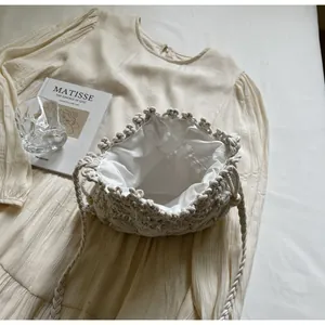 Detail view of woven bucket bag with cream cotton lining and thick braided shoulder strap