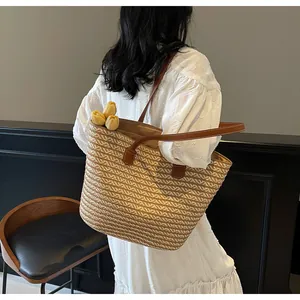Detailed view of the woven texture and dark brown leather straps on the summer straw tote