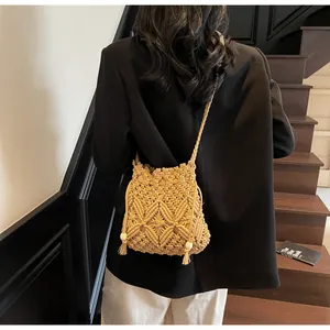 Detail of bohemian macrame bucket bag featuring geometric patterns and fringe with wood beads