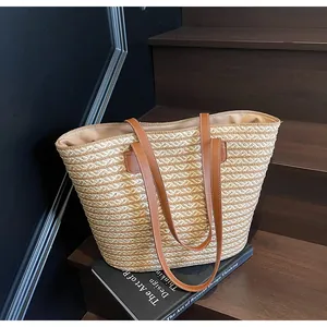 Detail of wave pattern woven straw tote bag with brown leather straps on wood stairs