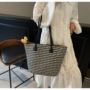Detail of woven tote bag showing black and white zigzag texture and leather handles