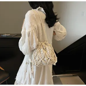 Detail of hand-woven cream crochet bucket bag with fringe tassels and diamond texture