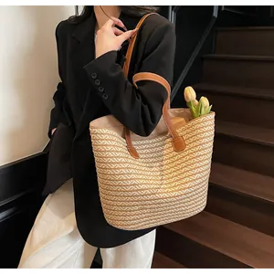 Detail of hand-woven straw tote bag with brown leather handles and natural texture