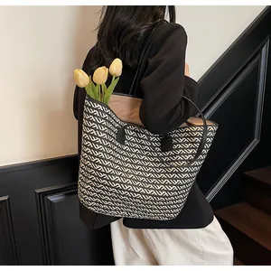 Detail of large woven tote bag with black and white zigzag patterns and leather handles