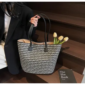 Detail of large woven tote bag with black and white geometric texture and leather straps