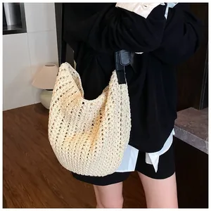 Gros plan du sac à bandoulière en crochet beige avec bandoulière en cuir noir texturé