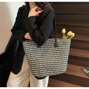 Detail of woven tote bag featuring black and white zigzag patterns and leather straps