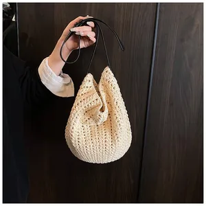 Détail de la texture crochetée beige avec une bandoulière en cuir noir nouée élégante