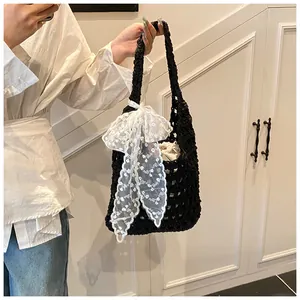 Detail der Häkeltasche mit großer weißer Spitzenschleife und Kordelzug-Innentasche