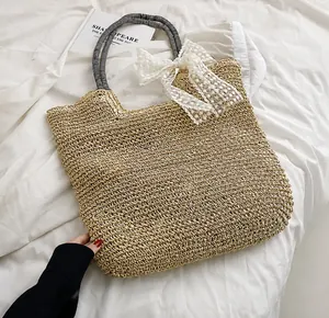 Détail du sac de plage en paille avec nœud en dentelle blanche et anses en corde