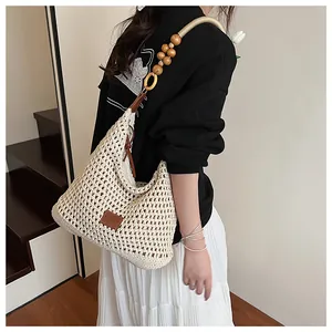 Detailed close-up of woven shoulder bag with natural wooden beads and leather logo tag