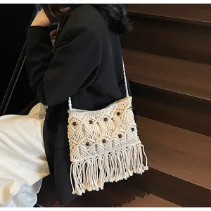 Detail of bohemian cream woven crossbody bag with brown beads and long fringes on model