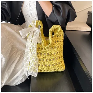 Detail der gelben Häkeltasche mit weißer Spitzenschleife und filigraner Lochmuster-Textur