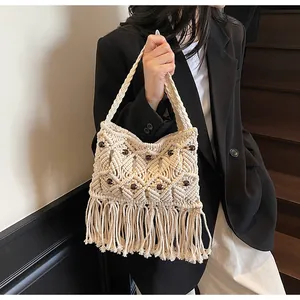 Detail of bohemian woven tote bag with wooden beads and long fringe on black blazer