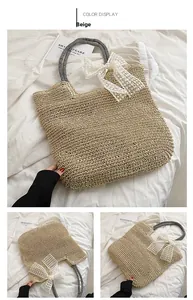 Detail der beigen Stroh-Strandtasche mit weißer Spitzenschleife und Streifengriffen