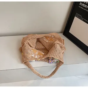 Detail of hollow knit tote bag with 3D colorful flower decorations on marble surface