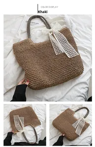 Detailansicht der khakifarbenen Strohtasche mit weißer Spitzenschleife und Griff