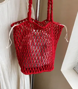 Detail of red hollow crochet knit tote bag showing the textured weave and drawstring liner