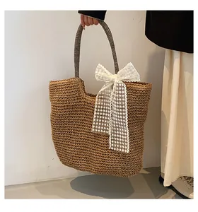Detail view of large straw tote bag with black patterned handles and white lace bow decoration