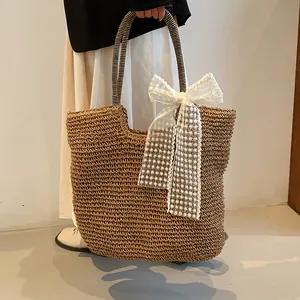 Detail of woven straw beach bag featuring a white lace bow and striped handle