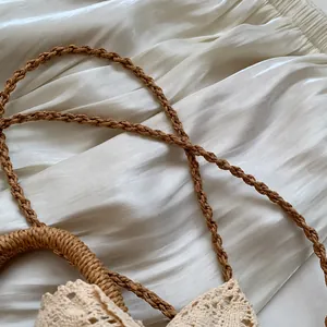 Detalle de la correa de paja trenzada con ribete de encaje beige para bolsos