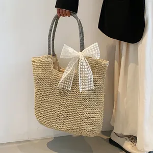 Detail of beige straw beach bag featuring a large lace bow and striped fabric handles