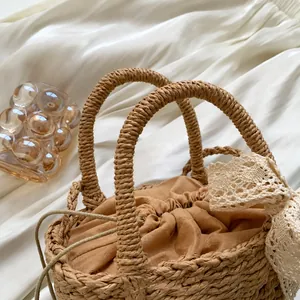 Detalle del bolso de playa trenzado con asas redondas dobles y lazo de encaje blanco