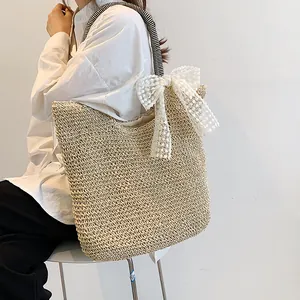 Straw tote bag detail with white lace bow and striped handles on light background