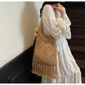 Close-up of bohemian woven tote bag with hollow mesh pattern and long tassel fringe details