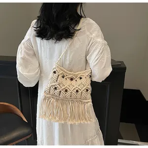 Detail of bohemian woven bag with ethnic fringe and wooden beads on a white dress model