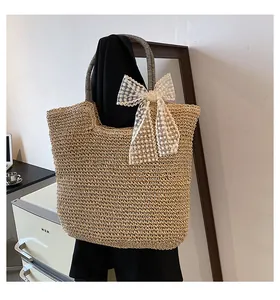 Close-up of handwoven straw tote bag with lace bow detail and striped handles