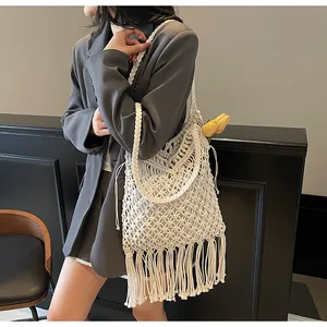 Close-up of handmade white crochet shoulder bag featuring long fringe and bohemian texture