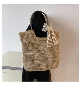 Detail of straw tote bag with striped handles and a large cream lace bow accent
