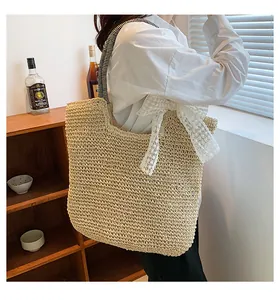Detail of woven straw tote bag with black striped strap and white lace bow decoration