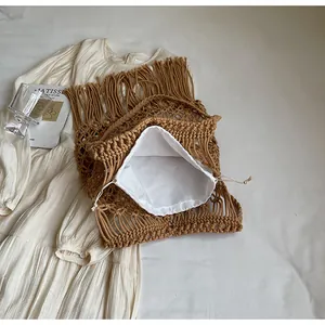 Close-up of caramel woven cotton bag with long fringes and a white drawstring inner pouch