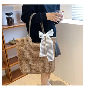 Detailed close-up of woven straw tote bag with white lace bow and striped rope handles