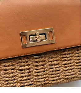 Detail of caramel leather and straw weave textures with a gold rectangular swivel lock