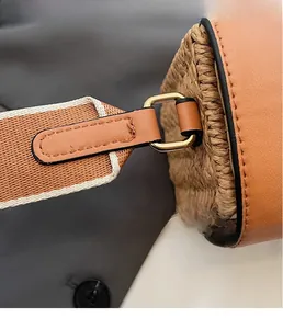 Detail of straw woven bag showing golden hardware buckle and brown leather texture