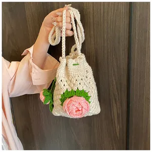 Detail der Strickstruktur der handgehäkelten Beuteltasche mit rosa Rose und Blättern