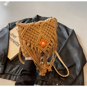 Détail d'un sac bohème tissé à franges avec fleur au crochet sur fond de cuir noir