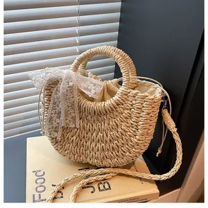 Dettaglio borsa in paglia beige intrecciata con fiocco in pizzo e sacca interna con coulisse