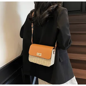 Close-up of handmade straw woven crossbody bag with brown leather flap and metal lock